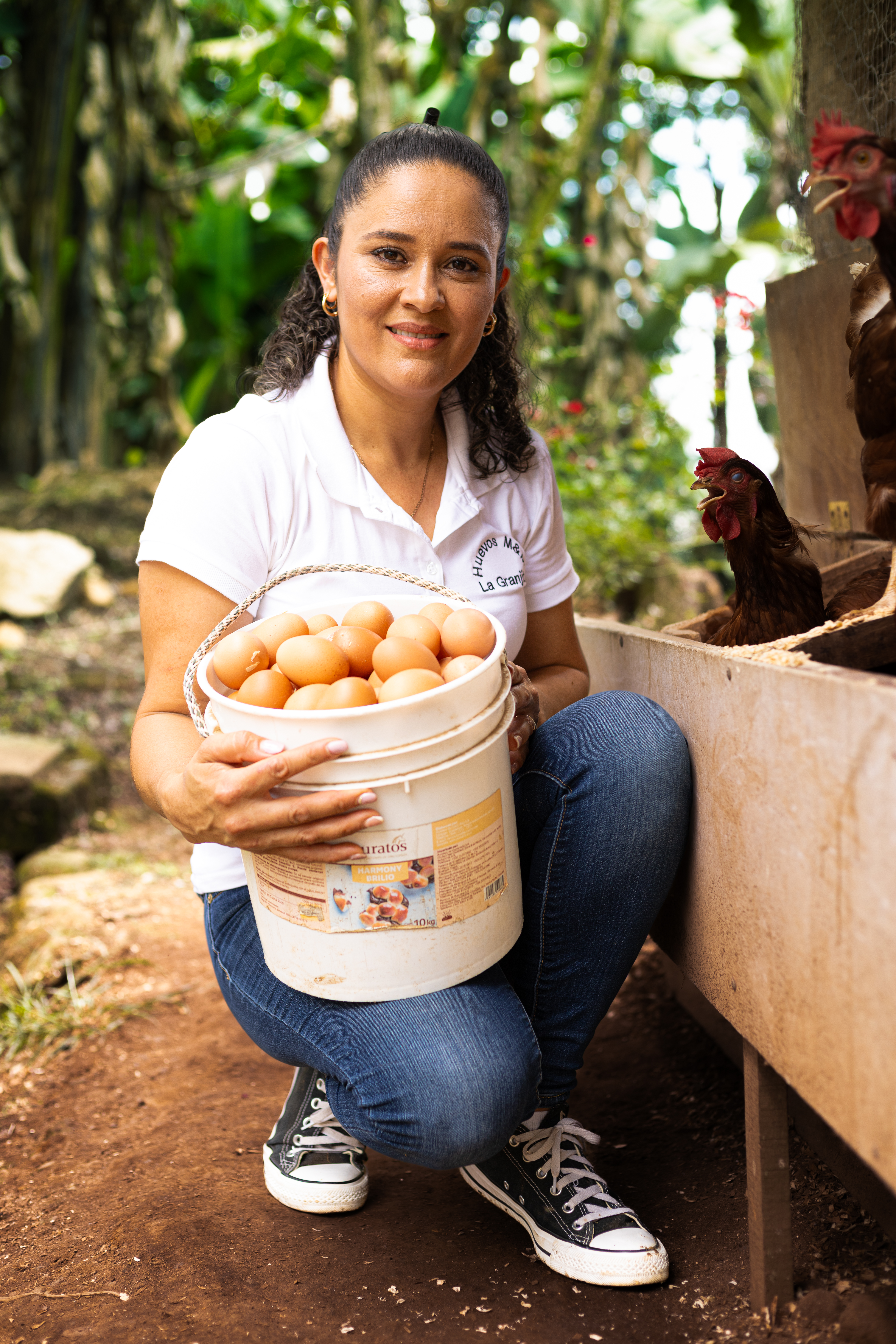 mujer recogiendo huevos de gallina que es su emprendimiento