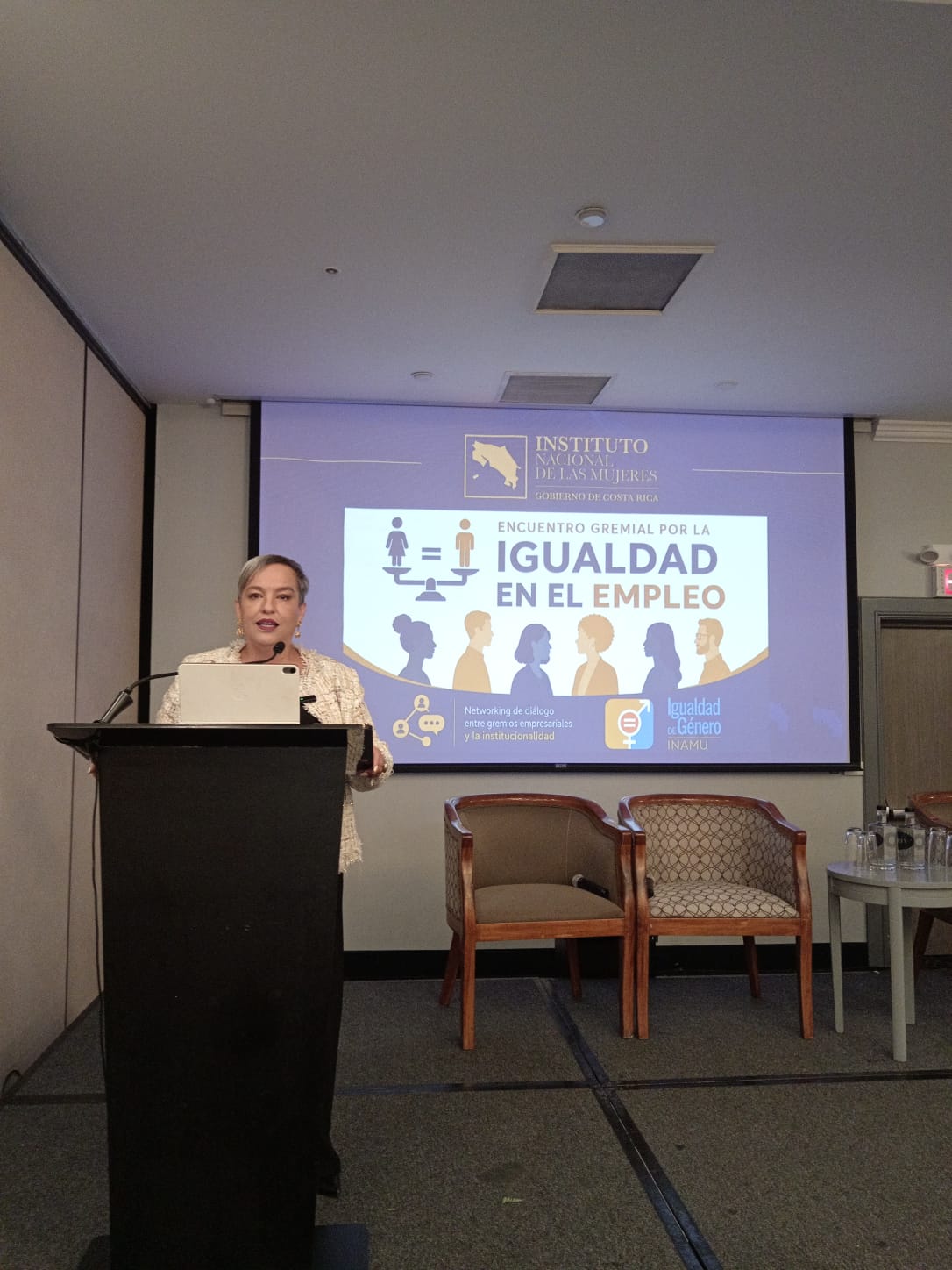 Carolina Delgado Ramírez, Presidenta Ejecutiva del INAMU en el podio con palabras de bienvenida al encuentro empresarial de cámaras
