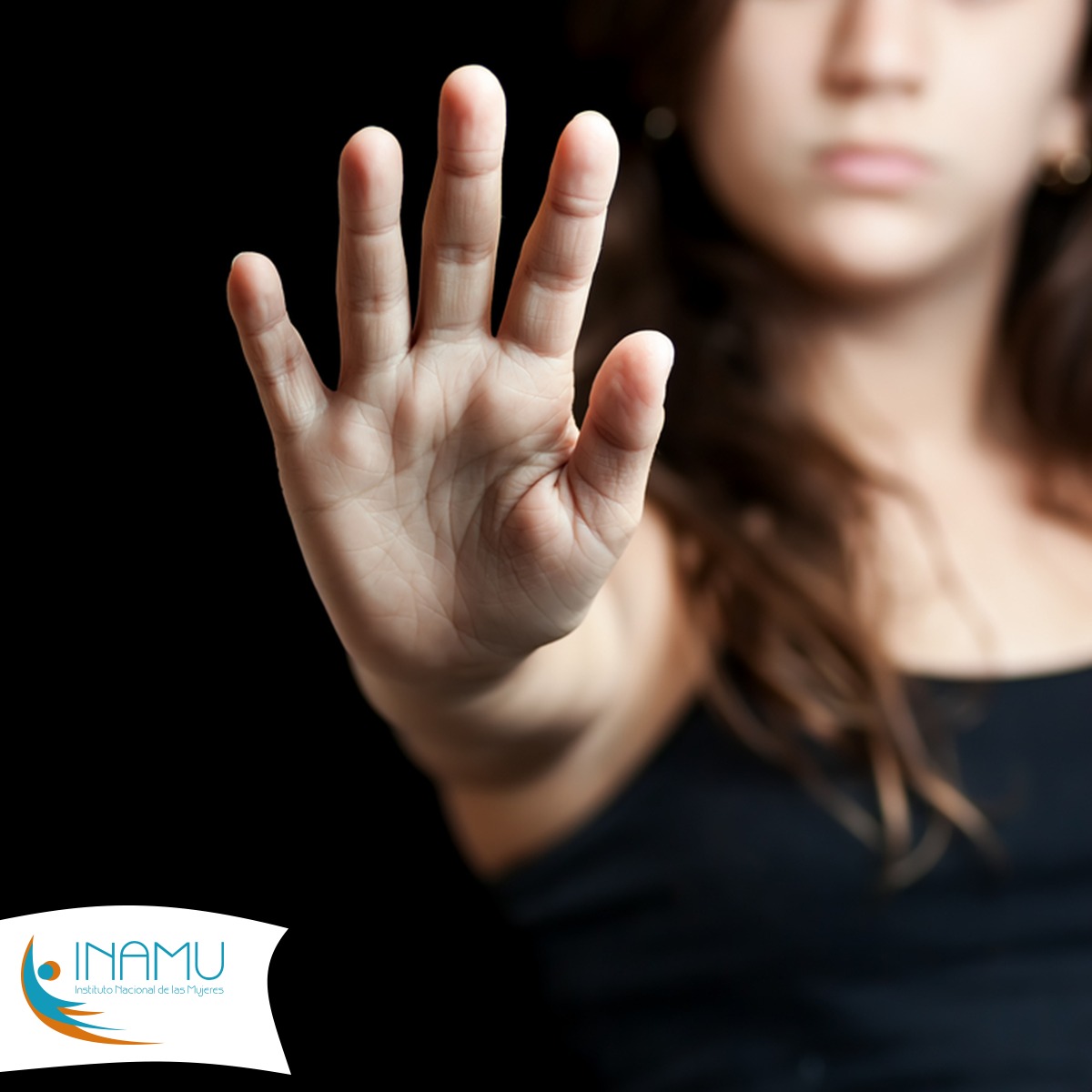 Una joven en blusa negra con la imagen distorcionada, se ve su mano en señal de alto con el logo institucional para dar a entender el alto a la violencia contra las mujeres